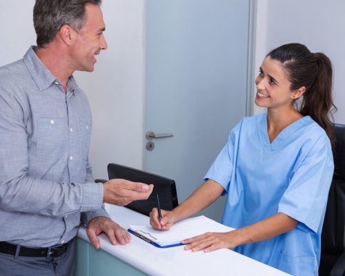 Smiling doctor and patient talking at desk in clinic